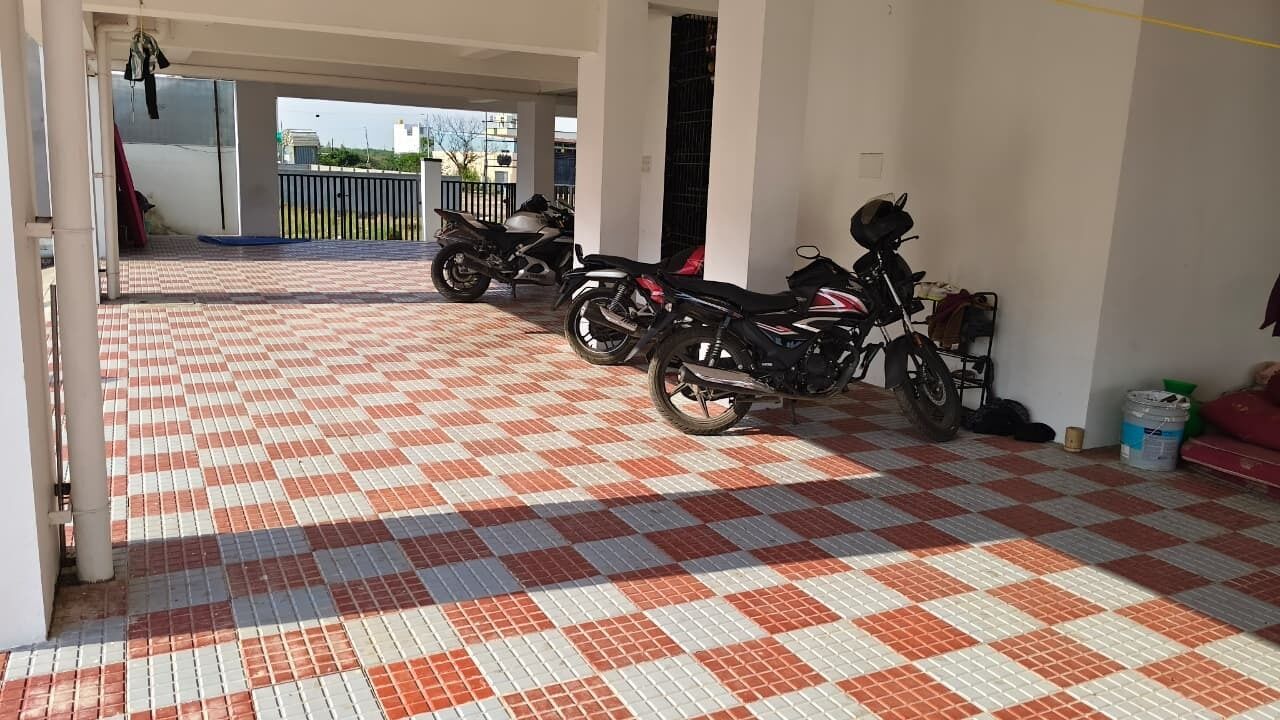 A covered parking area with a checkered floor, two motorcycles, and a red chair.