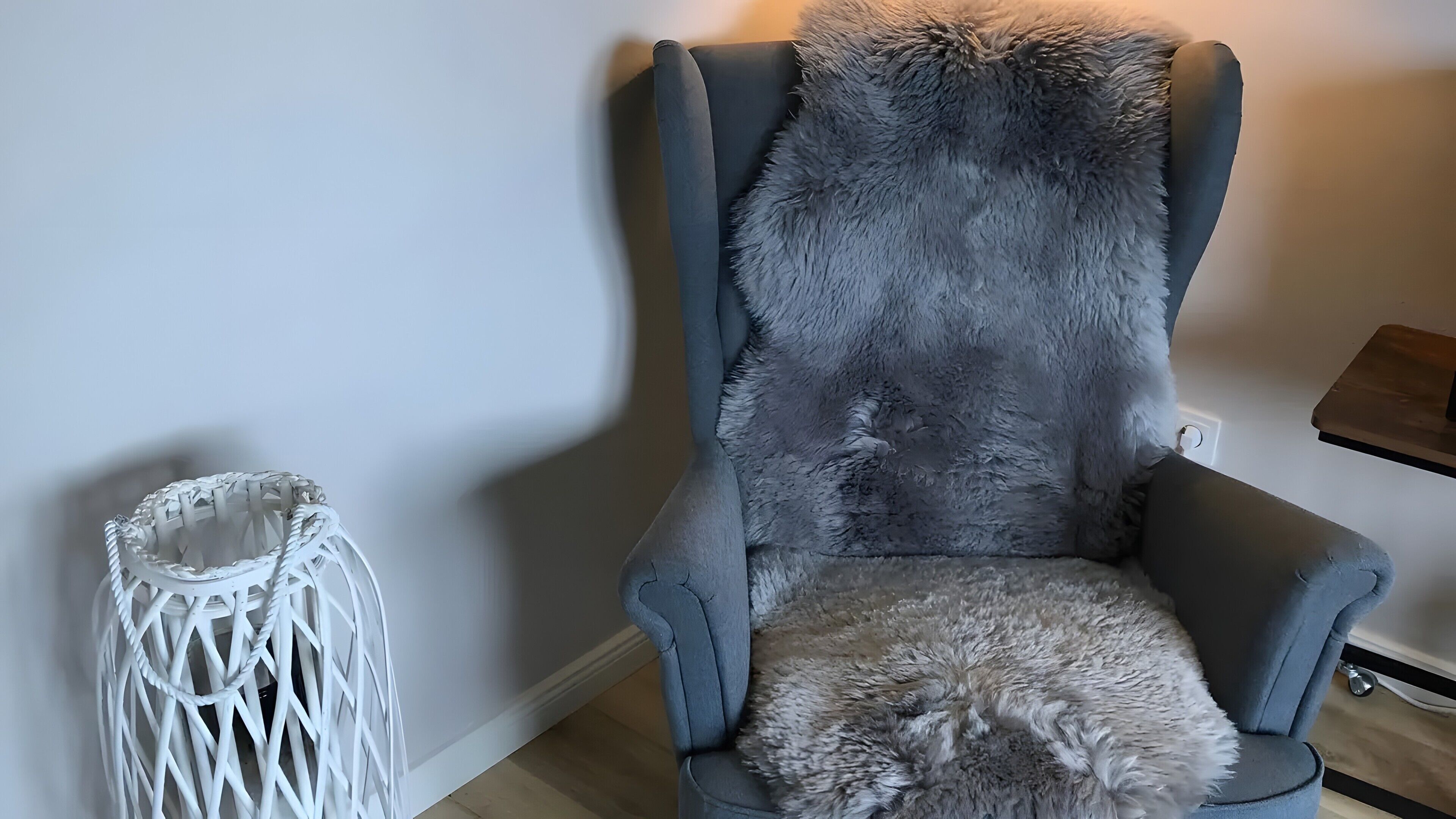 Un sillón tapizado de color gris con un respaldo mullido y una mesita auxiliar blanca de fibra.
