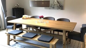Un espace repas avec une table en bois, des chaises noires et un banc.