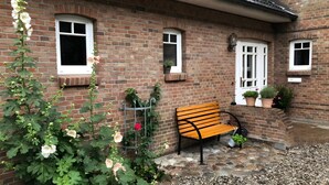 Un bâtiment en briques avec un banc, des plantes en pot et une fenêtre.