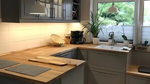 Une cuisine moderne avec un plan de travail en bois, une machine à café, un évier et des plantes en pot.