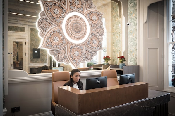 Una recepción con un muro decorativo, un área de estar y una computadora.