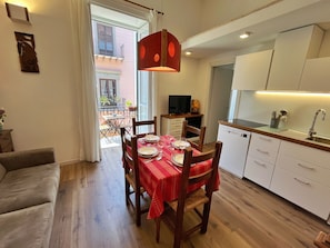 A compact living space with a dining area, kitchenette, and a view of the outside balcony. - Mafè Apt | Downtown & 5-Min Walk to the Station (Palermo)