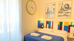 Une chambre d’hôtel avec un lit, une horloge murale et deux tableaux encadrés.