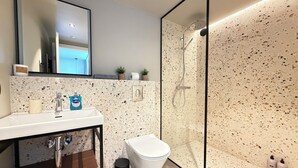 Un baño moderno con lavamanos, inodoro y ducha.