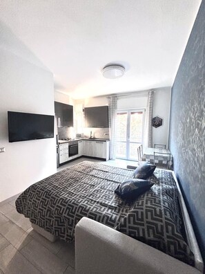 A compact room with a bed, a TV, a kitchenette, and a dining area. - Apartment on the Naviglio, Cozy Two-Room Apartment - Blue Line M4 (Lombardia)