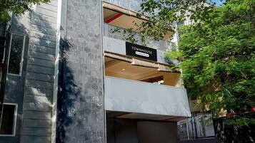 A modern townhouse with a balcony, a sign indicating it is company serviced, and a view of the surrounding greenery.