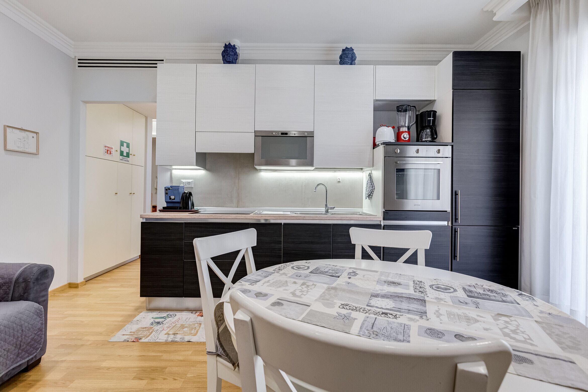 Een moderne keuken met witte kastjes, een ingebouwde magnetron en een roestvrijstalen oven.