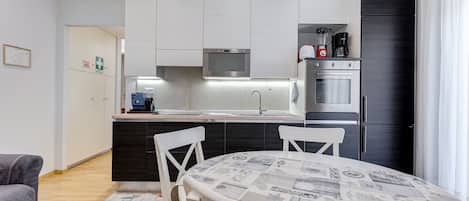 Una cocina moderna con armarios blancos, un microondas integrado y un horno de acero inoxidable.