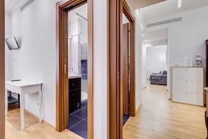 Ein modernes Interieur mit einer Holztür, einem weißen Schreibtisch, einem grauen Sofa und einem weißen Schrank.