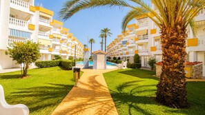 A hotel courtyard with a swimming pool, palm trees, and a pathway leading to the pool. - Ap2194 in Denia With 2 Bedrooms and 1 Bathrooms (Denia)