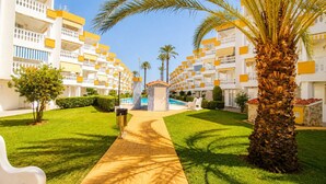 Ein Hotel mit zentralem Pool, umgeben von gepflegten Rasenflächen und Palmen.