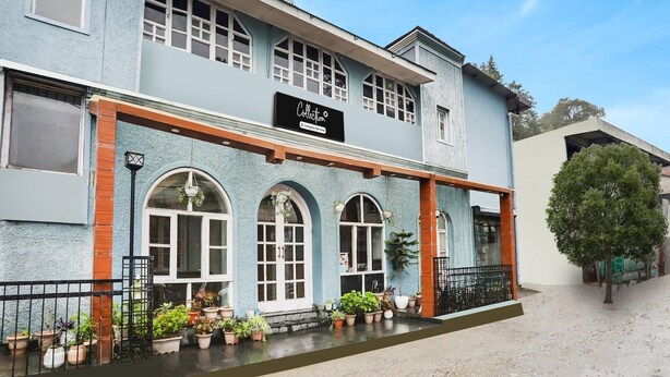 A building with a sign reading 'Collection,' featuring a light blue facade, multiple windows, and a balcony with potted plants. - Classic Villa Barlow (Dehradun)