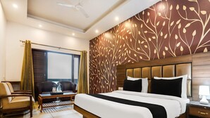 A hotel room with a large bed, a desk, a chair, a window, and a decorative wall. - Classic Villa Barlow (Dehradun)