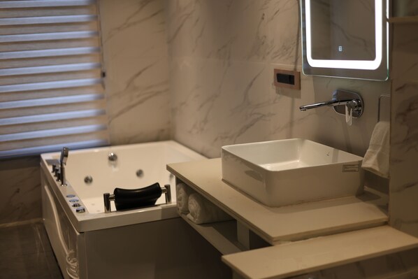 A modern bathroom with a bathtub, a sink, and a mirror.