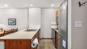 A compact kitchen with a wooden island, stainless steel appliances, and a tiled backsplash. - Whistler - Lost Lake Lodge - 1 Bedroom - 311 (Whistler)