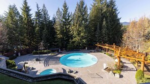 Ein runder Pool mit Holzterrasse und Holzpergola.