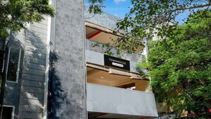 Una casa adosada moderna con un balcón, un cartel que indica servicio de empresa y vistas al entorno verde.