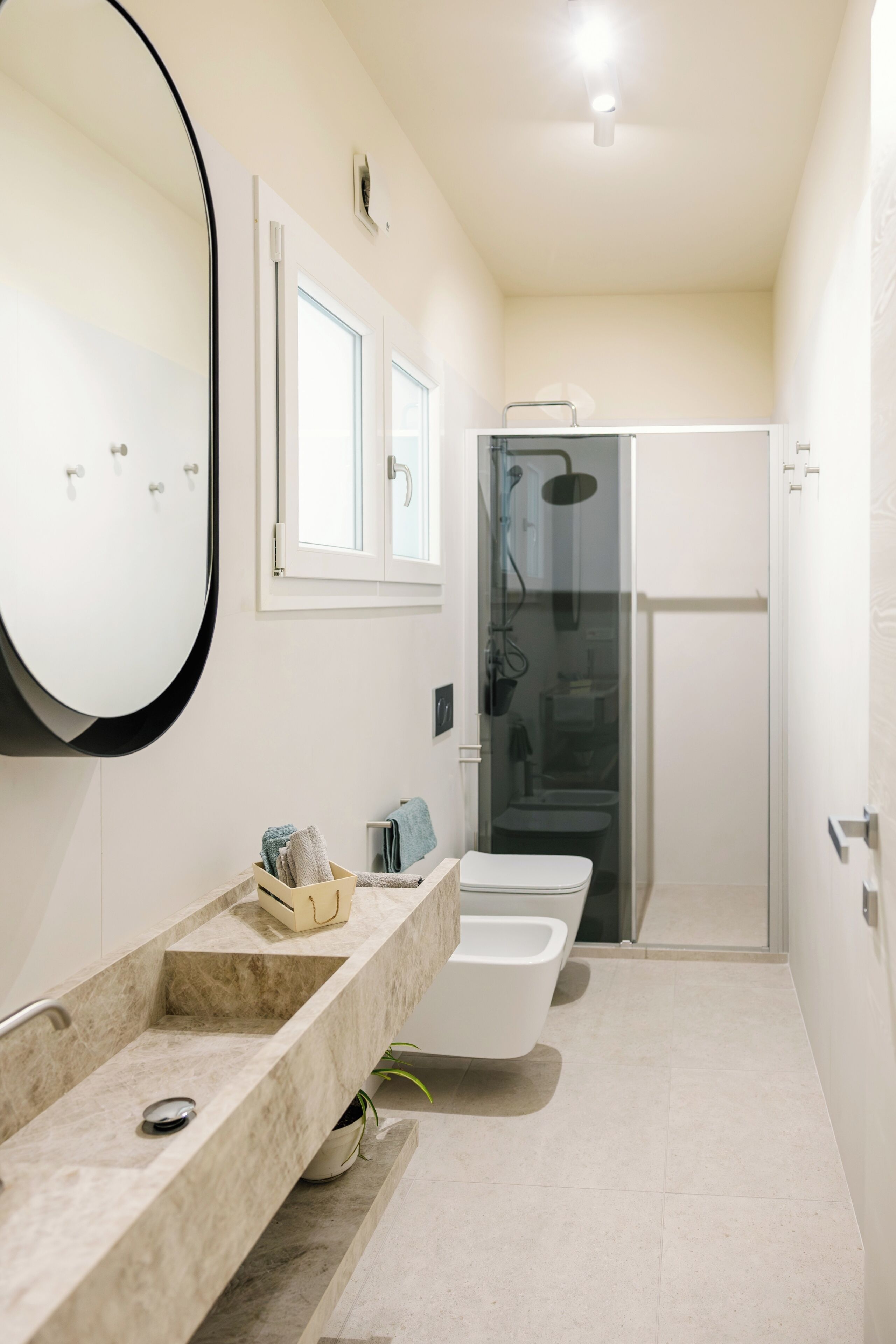 A modern bathroom with a large mirror, a shower enclosure, and a vanity with a sink and towel rack.