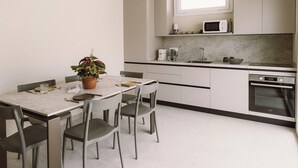Et moderne køkken med spisebord, stole, en potteplante, en mikrobølgeovn og en ovn.
