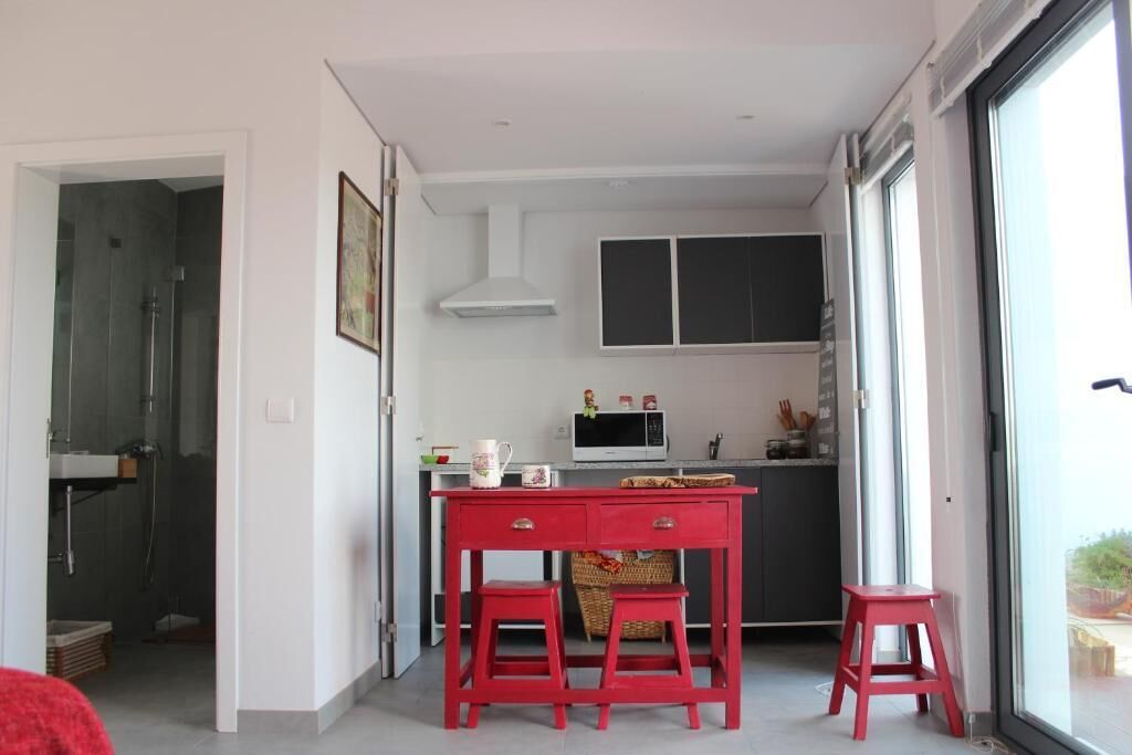 A modern kitchen with a dining area, a microwave, and a red table.