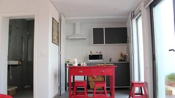 A modern kitchen with a dining area, a microwave, and a red table.