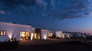 A modern building with multiple rooms, large windows, and a gravel driveway.