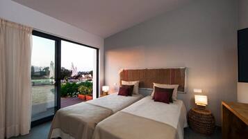 A hotel room with two beds, a balcony, and a view of a construction site.