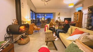 Una sala de estar acogedora con chimenea, asientos cómodos y vistas a través de un ventanal.