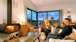 A cozy living room with a fireplace, comfortable seating, and large windows offering a view.