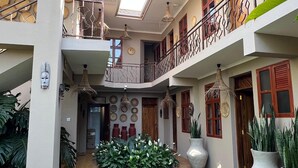 Un edificio de varios niveles con un patio central, balcones y plantas en macetas.