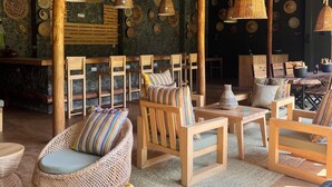 Un rincón de sala rústico con muebles de mimbre, techo tejido y platos decorativos en las paredes.