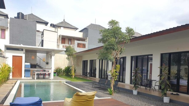 Zona residencial con piscina, mobiliario exterior y un pequeño jardín.