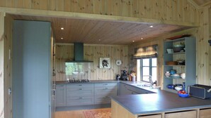 A kitchen with wooden walls, a gas stove, a sink, and a window with blinds. - 360-degree views from a mountain top in Numedal (Rødberg)