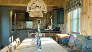 A wooden interior with a dining table, chairs, a woven light fixture, and a sofa with patterned cushions. - 360-degree views from a mountain top in Numedal (Rødberg)