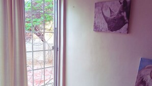 A room with a sliding glass door leading to an outdoor area with a brick floor and greenery. - Self-Catering Accommodation in Suiderhof, Windhoek (Windhoek)