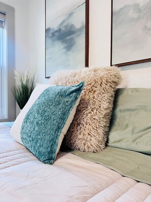 A bed with a quilted cover, a fluffy pillow, and a green pillow. There are framed artworks on the wall above the bed. - Cozy cottage: 3-bedroom in beautiful St. Petersburg (St. Petersburg)