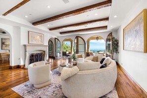 A spacious living room with a fireplace, comfortable seating, and large windows offering a view. - Bel Air Panorama - Mediterranean Estate w/ Resort-Style Grounds (Bel Air)