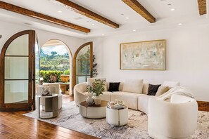 A modern living room with a sectional sofa, a coffee table, and a large painting on the wall. - Bel Air Panorama - Mediterranean Estate w/ Resort-Style Grounds (Bel Air)