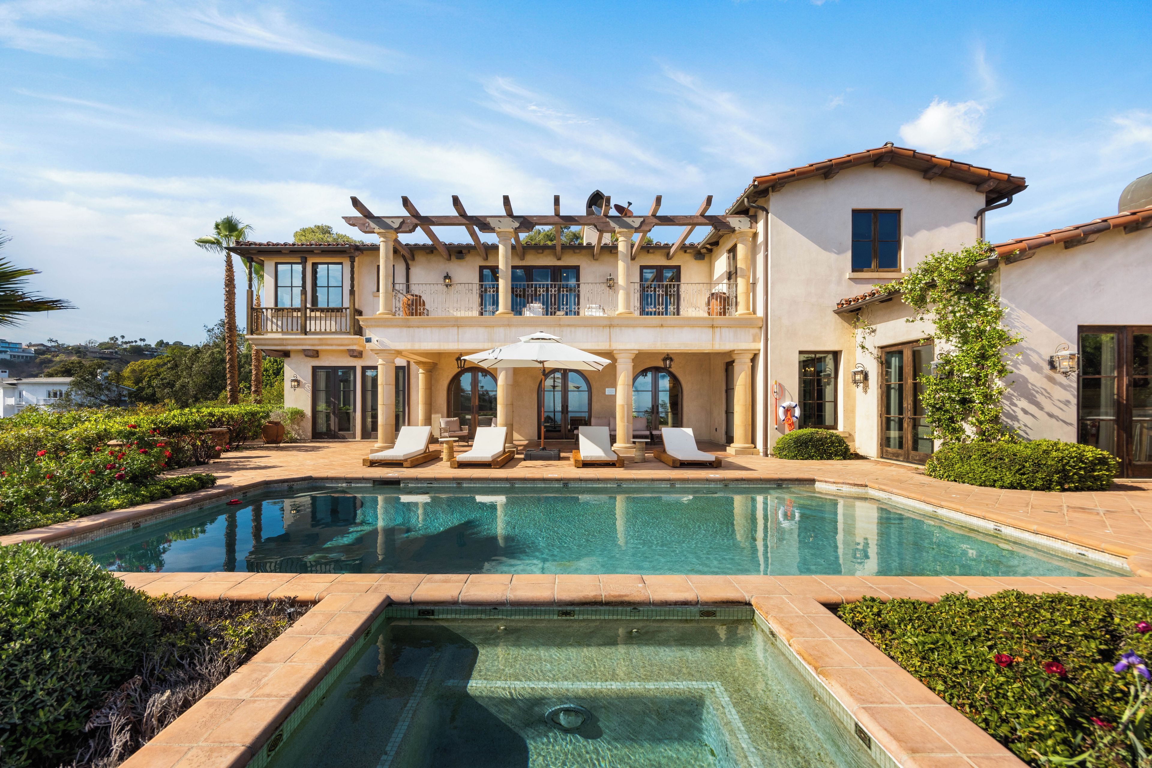 A two-story house with a swimming pool, outdoor seating, and a pergola.