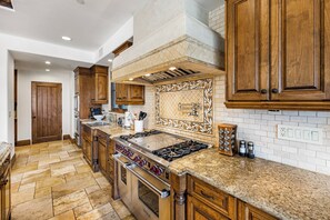 A kitchen with wooden cabinets, a gas stove, and a tiled backsplash. - Bel Air Panorama - Mediterranean Estate w/ Resort-Style Grounds (Bel Air)