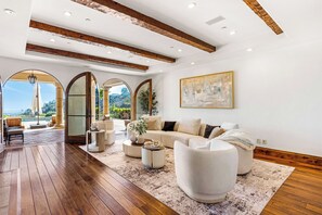 A spacious living area with a wooden floor, a large sofa, a coffee table, and a painting on the wall. - Bel Air Panorama - Mediterranean Estate w/ Resort-Style Grounds (Bel Air)