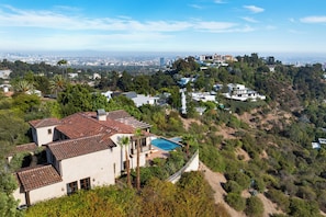 A residential area with a large house featuring a swimming pool, surrounded by dense vegetation and a hilly landscape. - Bel Air Panorama - Mediterranean Estate w/ Resort-Style Grounds (Bel Air)