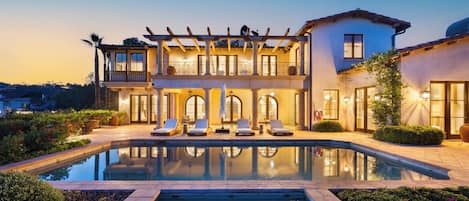 A two-story building with a pool, outdoor seating, and a well-lit facade.