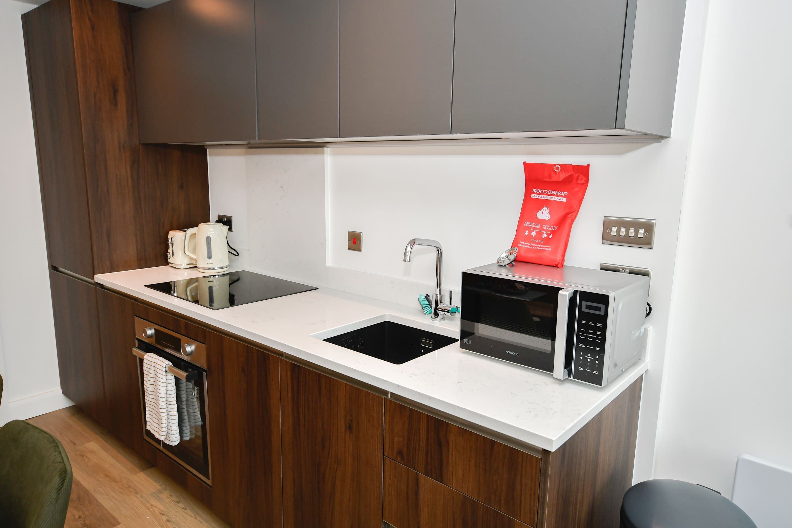 A modern kitchen with a double sink, a microwave, and a kettle.