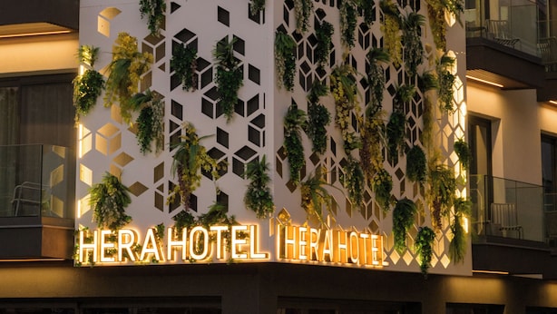 A hotel facade with a geometric pattern, vertical greenery, and illuminated signage. - Hera Hotel Axd (Alexandroupoli)