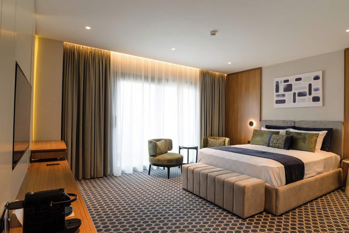 Una habitación de hotel con una cama grande, un escritorio, una silla y un televisor.
