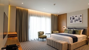 A hotel room with a large bed, a desk, a chair, and a television. - Hera Hotel Axd (Alexandroupoli)