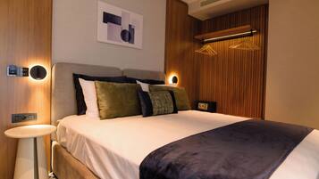 Una habitación de hotel moderna con una cama grande, mesitas de noche, una obra de arte en la pared y un revestimiento de pared de madera.