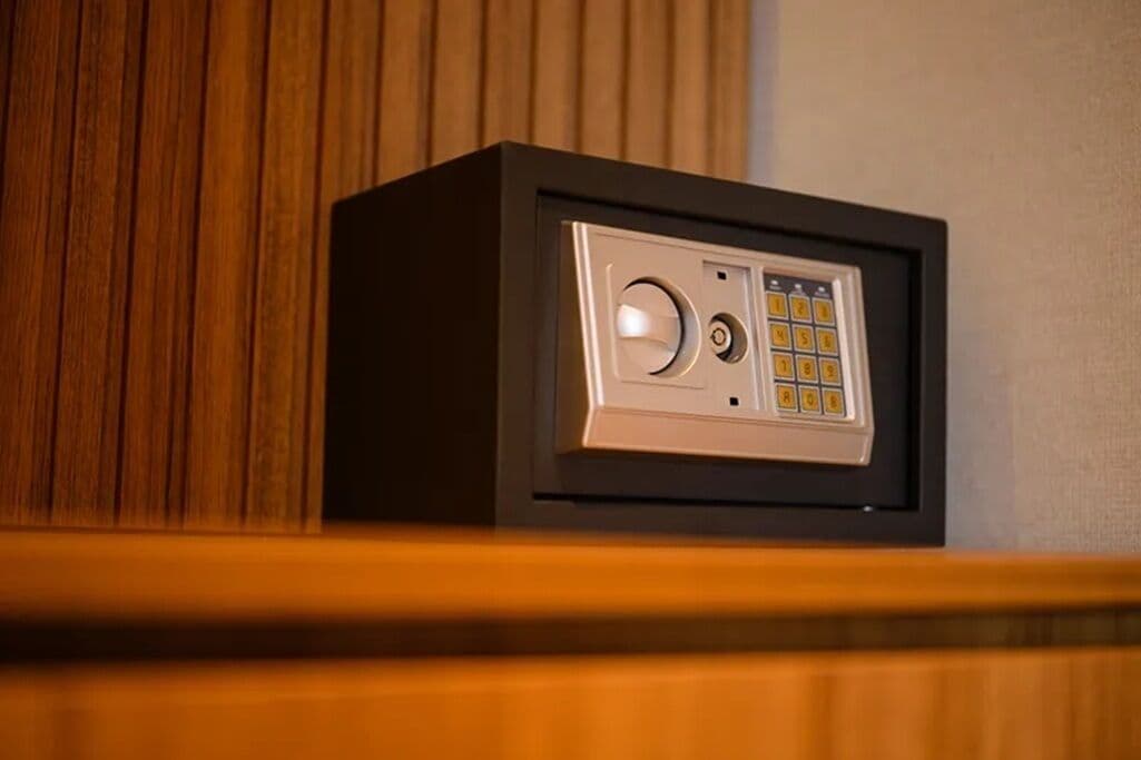 Una caja fuerte con teclado y mecanismo de cierre circular, ubicada sobre un repisa de madera.